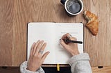 Picture of a hand holding a pen making a list in a notebook