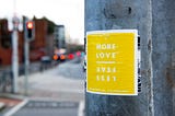 an image of a yellow poster that says “more love” “less fear” on a wall