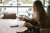 Photo of a woman sat at a table looking at a menu with a neutral/blank expression