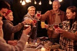 A party of people toasting with their glasses at night outside.