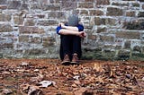 A frustrated man sitting against a wall