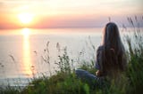 woman sitting by ocean being still and listening for God