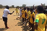 Ashoka Fellow Elvis Nshimba talking to a group of sports players in yellow jerseys.