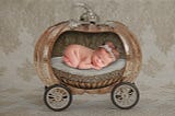 newborn baby in a golden pumpkin carriage