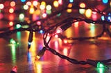 a strand of pink, green and yellow holiday lights is lying on a hardwood floor in a dark room