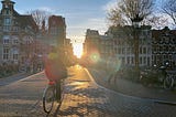 A bicycle crosses a bridge at sunset in the canal city of Amsterdam.
