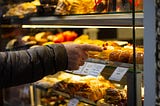 person choosing one pastry from a display case