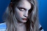 Young blonde woman glaring at camera with clearly edited eyes. Meant to portray sinister or evil glare.