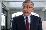 Robert DeNiro, a senior aged intern in the movie The Intern, wearing a suit and tie.