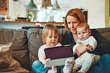 Mother looking at content on ipad with her two young children