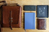 A picture of my satchel, notebook, ereader, pocket, and battery