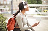 Woman with headphones on audio journaling with her phone while sitting down outside
