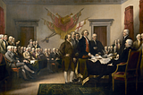 Painting called “Declaration of Independence” of an 18th century scene. Five white men stand in a fancy hall to present a seated man with a paper. Two rows of mostly seated men look on.