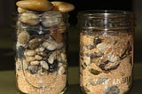 Two jars. One overloaded with sand coming first and one filled with bigger rocks coming first then covered with sand.