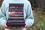 A girl holding a stack of fantasy books