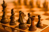Closeup of a wooden chess board with wood chess pieces.