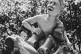 A happy human-like being emerges from a statue of a vice-like robotic grip.