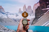 Compass held in front of mountains.