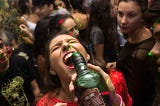 Woman being poured a drink from a bottle at a party