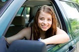 Pretty young girl smiling from driver’s die window.