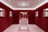 Glossier’s scene showroom has lilac carpeted floors and deep red velvet fabric covers the walls floor to ceiling.