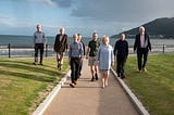 8 people of our team on a coastal path of the Slieve Donard — with the mountains of mourne and the sea in the background