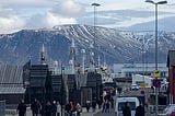 Walk along street leading to Reykjavik Harbor with snow-capped mountains in background.