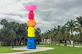 Large scale colorful sculpture at the square with palm trees