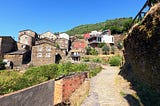 A narrow, rocky path leads to a village full of house made of schist rock