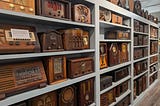 A series of bookcases filled with dozens of antique radios, most in wooden cabinets.