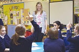 A classroom where some students raise hands for speaking