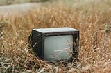 An old television sitting in a field.