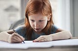 A little girl writing on paper