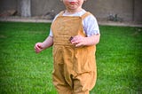 Image of a toddler standing on a lush green lawn.