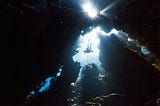 A figure diving deep into the ocean through rocks