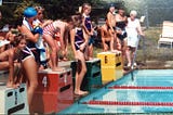 Young children on diving blocks at the start of a swim race