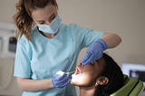 A dentist woman treating a woman patient.