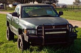 A truck with a ‘For Sale’ sign in the front windshield.