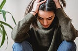 Woman suffering from chronic migraine holding her head in pain.