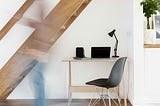 a shade of a man leaving a work  desk with a laptop on in a home setting