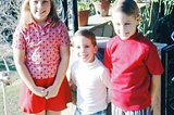 A young white girl about eight, a little guy in the middle, probably three years old and another brother, on the far right, who’s about five or six. We’re all wearing patriotic, if not oddly cobbled together, outfits. Circa 1970.
