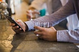 man at bar drink while using his phone