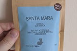 Bag of coffee beans. Labels state “Whole Bean”, “Santa Maria” “Antigua Guatemala” includes tasting notes and roast date of the coffee.