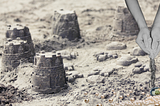 broken sandcastles with hands sifting grains of sand into oyster shells and pearls