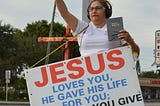 Sidewalk sandwich board carrier with John 3:16.