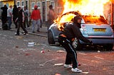 London Riots of 2011. Man in front of blazing car throws something