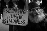 Michael, a homeless man in Boston subway station, holding a sing where is written “Seeking human kindness”