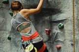 Woman ascending an artificial rock climbing structure.