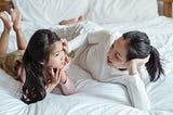 Mother lovingly talking to her daughter on a bed.