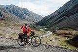 Robbie gives a thumbs up with a bikepacking bike in an alpine landscape